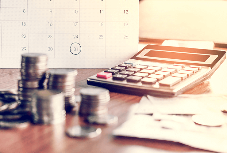 calculator and coins on a table in front of a calendar