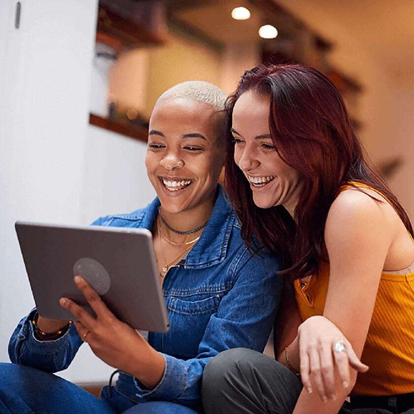 two women smiling at a tablet