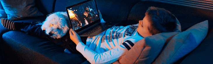 young boy watching a movie on his computer with a dog on his lap