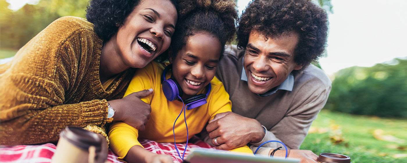 Family on a picnic enjoys streaming with their tablet in a park - every day feels festive this fall with top movies and shows from Prime Video, Hulu and Netflix!