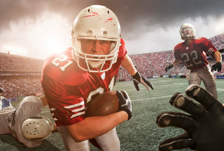 Big Game player holds football and runs straight at the viewer