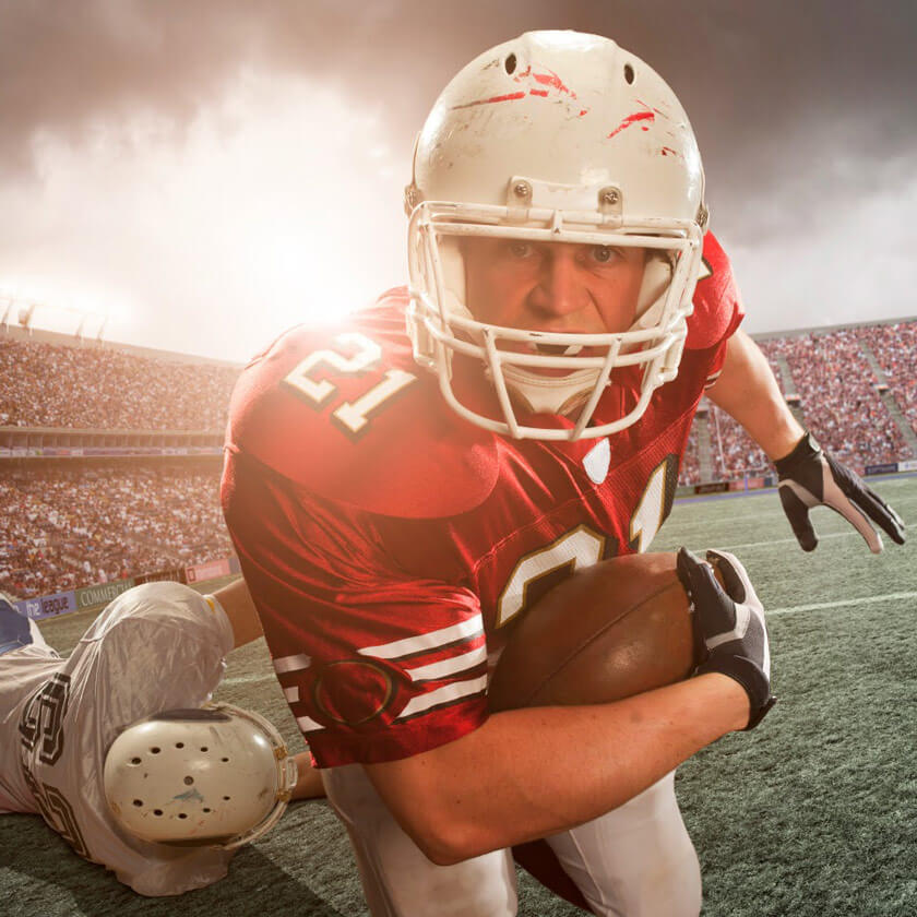 Big Game player holds football and runs straight at the viewer