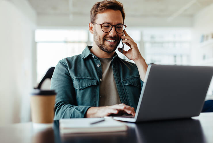 Man on mobile phone and laptop switching phone carriers